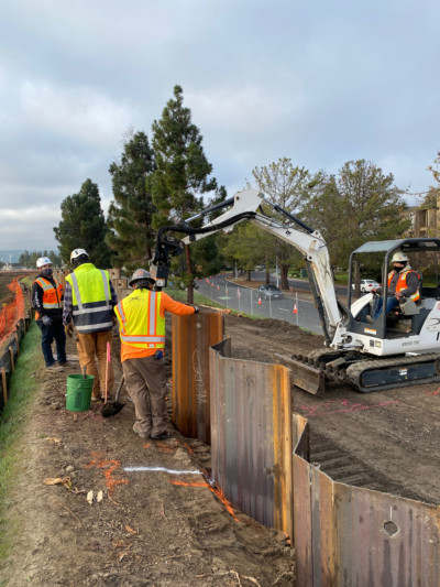 Construction workers install sheet piles