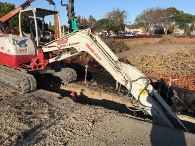 Tractor digging up ground to install sheet piles